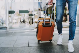 Person rolling suitcase in an airport